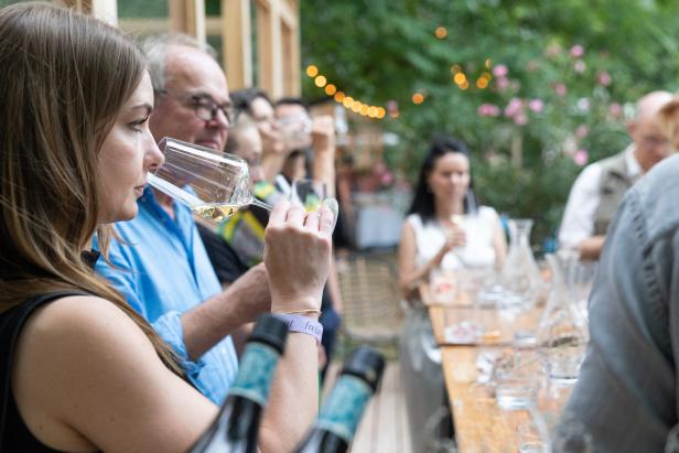 Eine Frau probiert Wein bei einer Weinprobe im Freien.