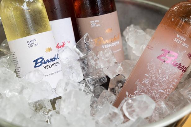 Verschiedene Flaschen Burschik Vermouth liegen in Eiswürfeln.