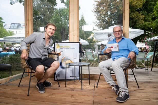 Zwei Männer sitzen auf einer Bühne im Freien beim „Liquid Market Vienna Cocktail Festival“.