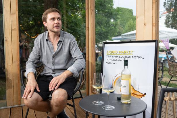 Ein Mann sitzt neben einem Tisch mit Getränken beim „Liquid Market“ Cocktail Festival in Wien.