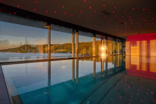 Ein Innenpool mit Blick auf einen See bei Sonnenuntergang.