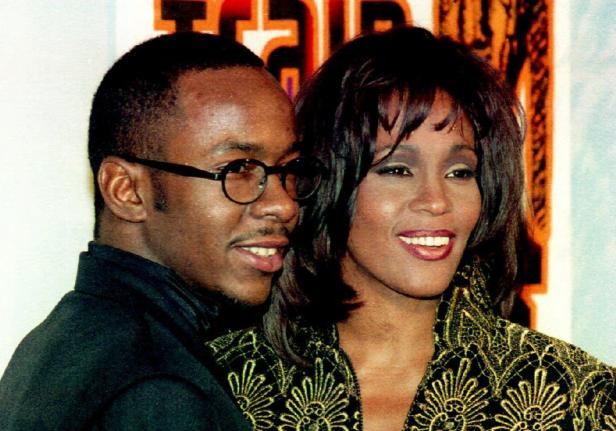Bobby Brown und Whitney Houston posieren lächelnd für ein Foto.