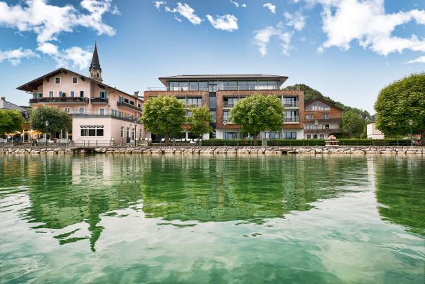 Blick über das Wasser auf eine Stadt mit Hotels und einer Kirchturmspitze.