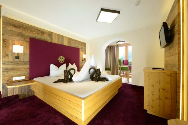 Ein Hotelzimmer mit Holzwand, großem Bett und Schwanen-Handtuchfiguren.