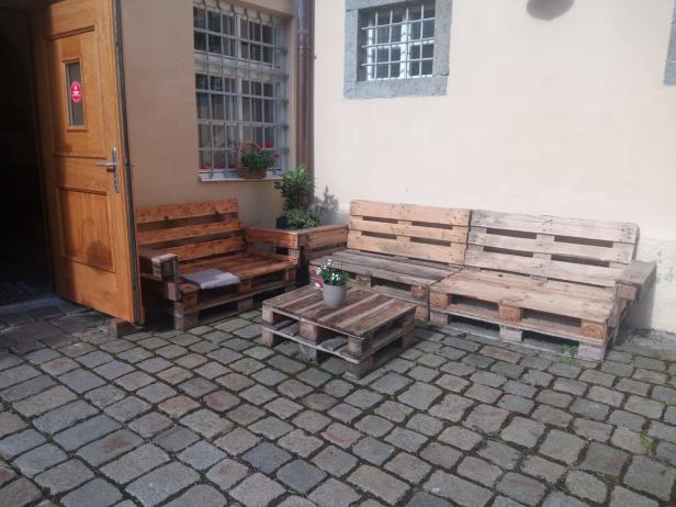 Eine Sitzecke mit Möbeln aus Europaletten in einem Innenhof.