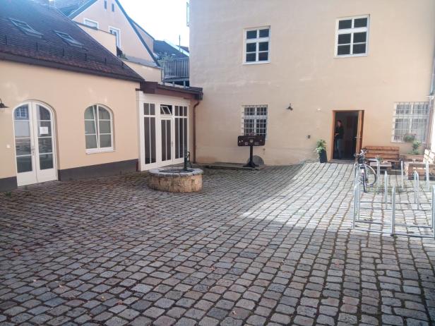 Ein Innenhof mit einem alten Brunnen und einem Gebäude im Hintergrund.