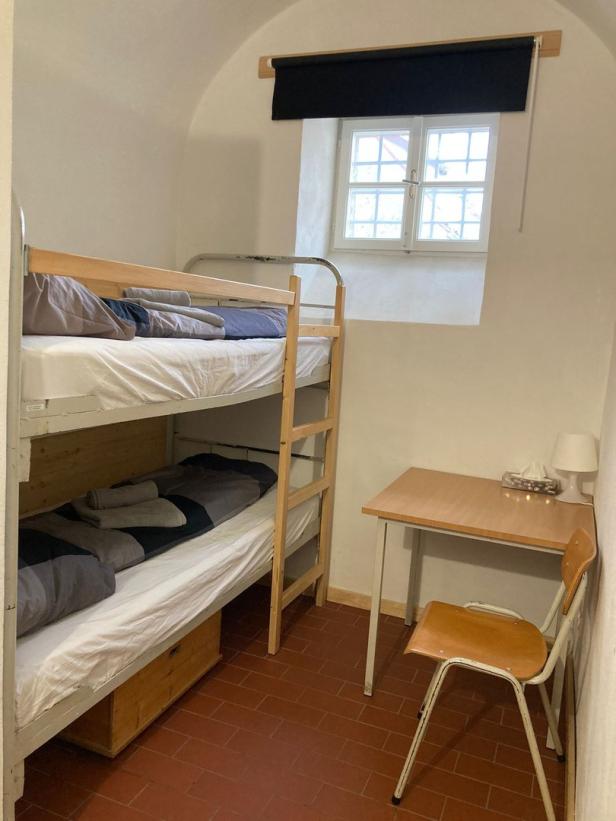 Ein einfaches Zimmer mit einem Etagenbett, einem Schreibtisch und einem Stuhl.