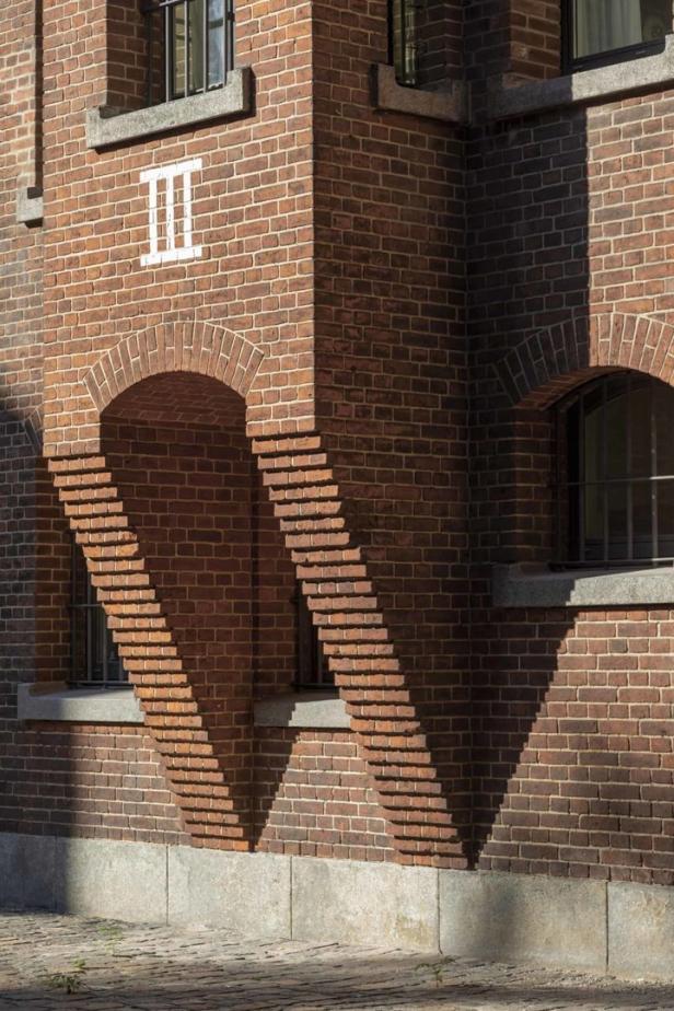 Detailaufnahme einer roten Backsteinfassade mit einem weißen „III“-Schriftzug.