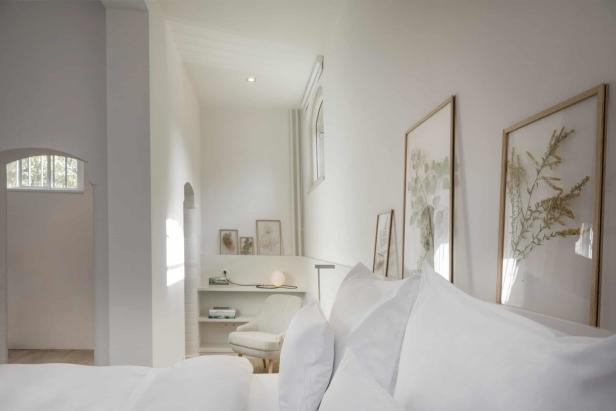 Ein helles Schlafzimmer mit weißen Wänden und botanischen Kunstdrucken.