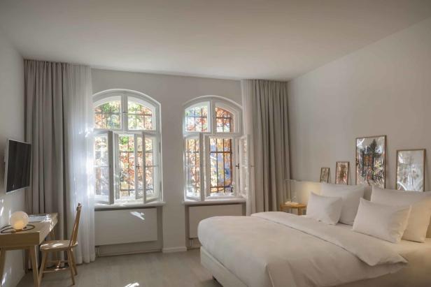 Ein helles Schlafzimmer mit zwei Fenstern und einem großen Bett.