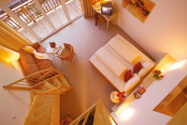 Blick von oben auf ein helles, gemütliches Hotelzimmer mit Treppe.