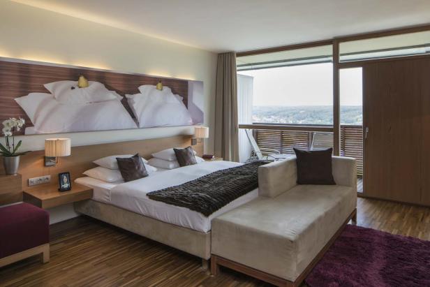 Ein modernes Hotelzimmer mit Doppelbett und Balkon mit Ausblick.