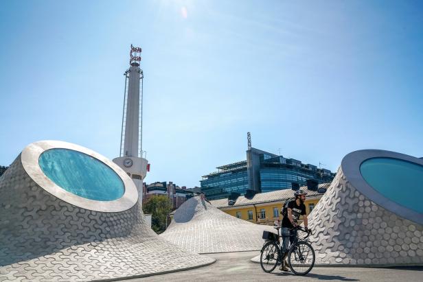 Ein Radfahrer vor dem Amos Rex Museum in Helsinki mit dem markanten Schornstein im Hintergrund.