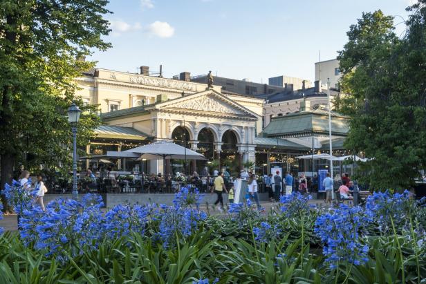 Das Restaurant Kappeli in Helsinki, mit Menschen und blauen Blumen im Vordergrund.