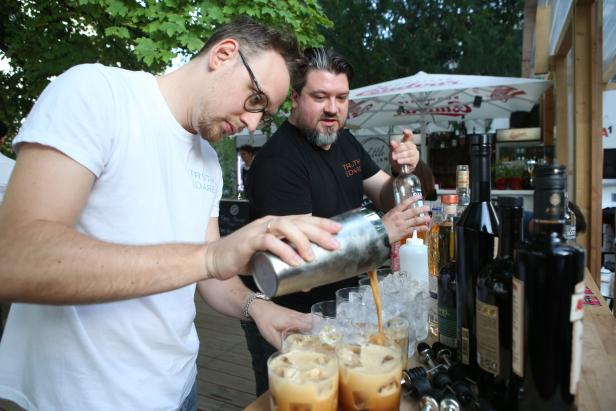 Zwei Barkeeper mixen Cocktails an einer Bar im Freien.