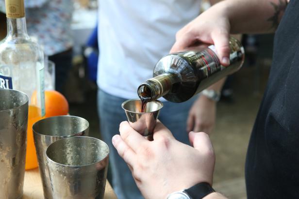 Eine Person gießt eine dunkle Flüssigkeit aus einer Flasche in einen Messbecher.