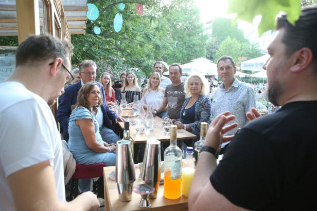 Eine Gruppe von Menschen sitzt an einem Tisch im Freien und unterhält sich.