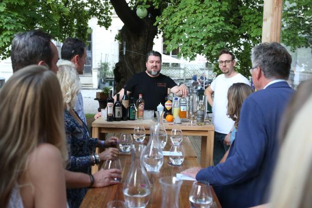 Ein Barkeeper bereitet im Freien Getränke für eine Gruppe von Menschen zu.