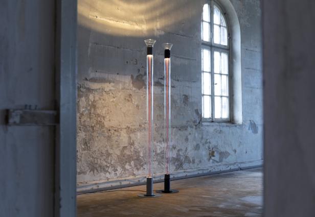 Zwei moderne Stehlampen stehen in einem Raum mit abblätternder Farbe neben einem Fenster.
