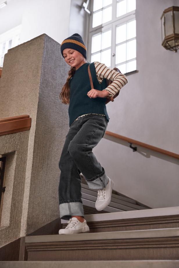 Ein junges Mädchen mit Rucksack geht eine Treppe hinunter.