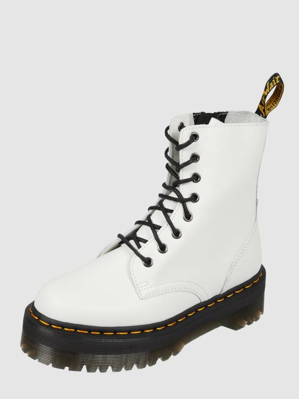 Ein weißer Dr. Martens Schnürstiefel mit schwarzer Sohle und Schnürsenkeln.