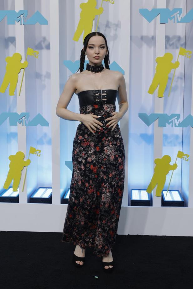 Dove Cameron posiert in einem trägerlosen Kleid mit Blumenmuster auf dem schwarzen Teppich.