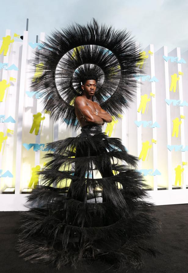 Lil Nas X in einem extravaganten schwarzen Federkleid auf dem roten Teppich.