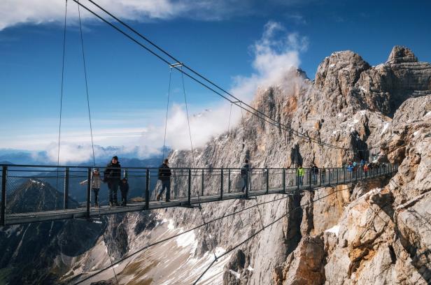 Menschen überqueren die Hängebrücke am Dachstein.