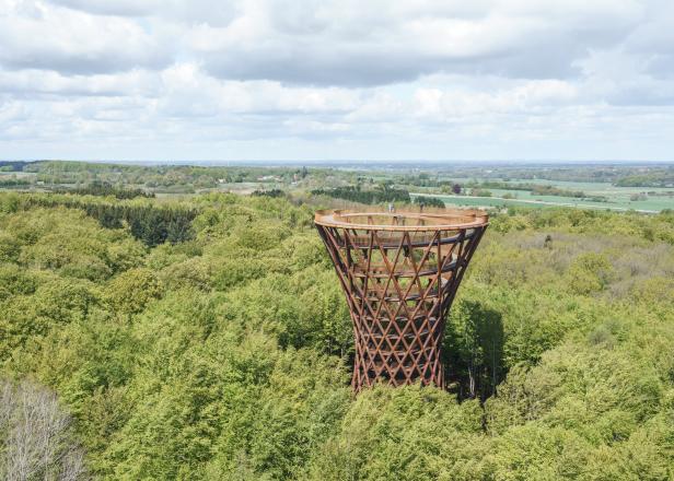 Der spiralförmige Aussichtsturm „Skoven“ ragt über die Baumkronen eines Waldes.