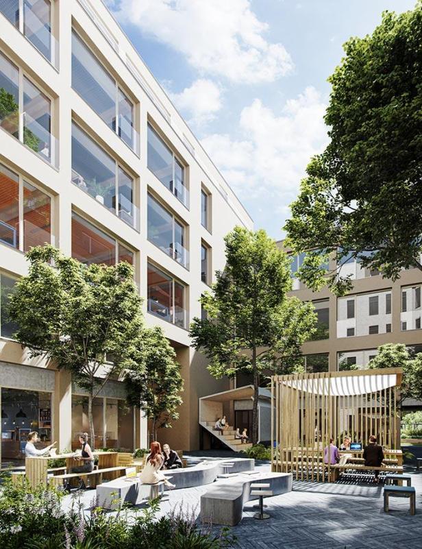 Ein Innenhof mit Sitzgelegenheiten und Grünflächen zwischen modernen Gebäuden.