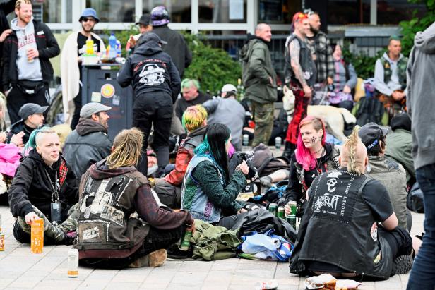 Eine Gruppe von Punks sitzt im Freien und unterhält sich bei Getränken.
