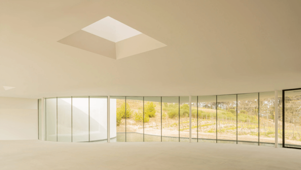 Der Oscar Niemeyer Pavillon mit Blick auf einen Weinberg durch eine Glaswand.