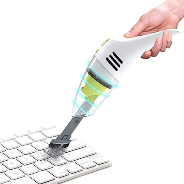Ein Handstaubsauger reinigt eine weiße Computertastatur.