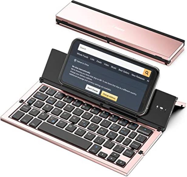 Ein Smartphone steht auf einer zusammenklappbaren, roségoldenen Tastatur.