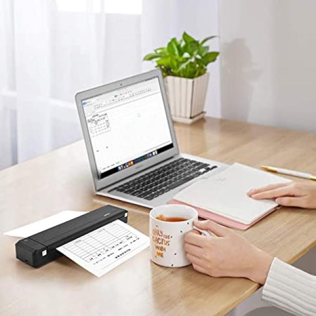 Eine Person arbeitet an einem Laptop und druckt ein Dokument mit einem tragbaren Drucker.