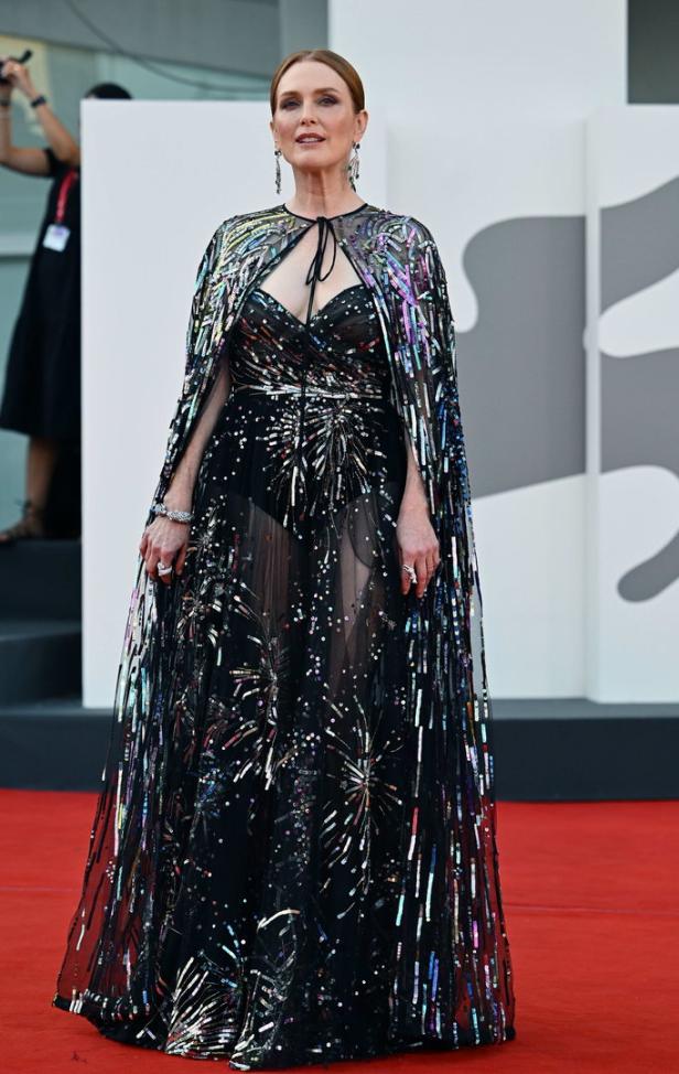 Julianne Moore in einem schimmernden, bodenlangen Kleid mit Cape auf einem roten Teppich.