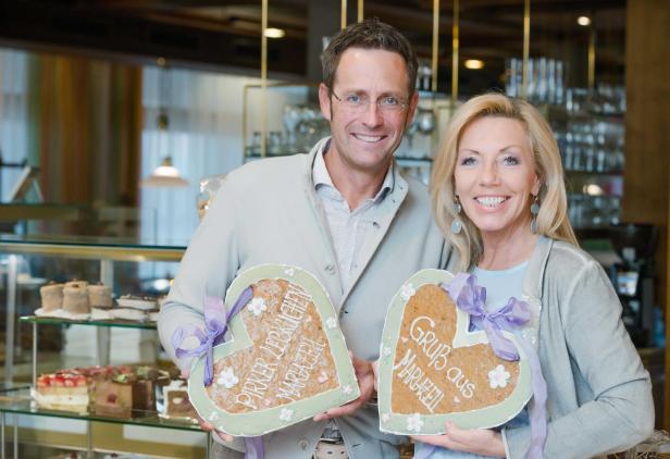 Ein Mann und eine Frau halten Lebkuchenherzen mit der Aufschrift „Pirker Lebkuchen Mariazell“ und „Gruß aus Mariazell“.