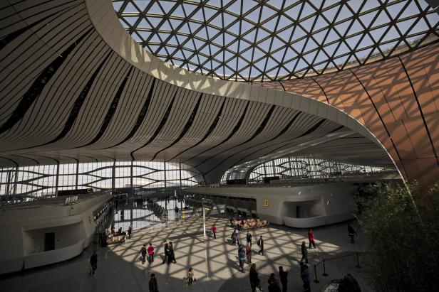 Menschenmenge in einem modernen Flughafen mit Glasdach und markanter Architektur.