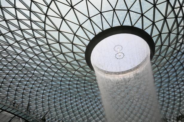 Ein Wasserfall ergießt sich von der Decke eines Gebäudes mit Glasdach.