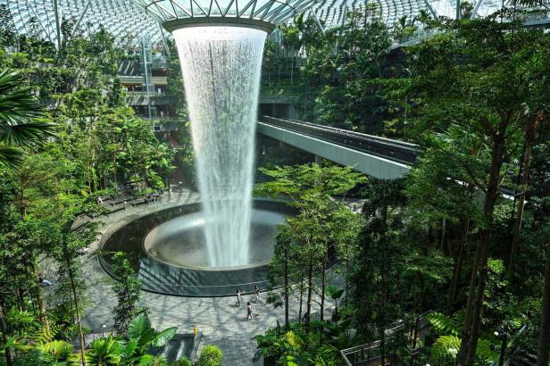 Ein großer Wasserfall ergießt sich in einem üppigen, begrünten Innenraum.