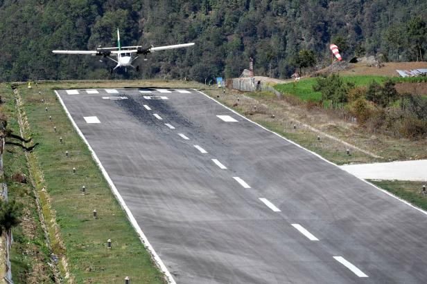 Ein Flugzeug landet auf einer Landebahn in einer bergigen Gegend.