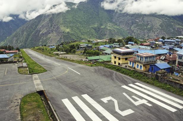 Blick auf die Landebahn des Flughafens Lukla in Nepal vor einer Bergkulisse.