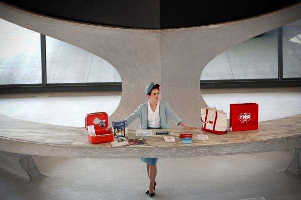 Eine Frau in Uniform steht hinter einem Schalter im TWA Hotel mit Retro-Accessoires.