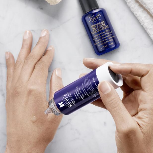 Eine Hand tropft Kiehl's Retinol Serum auf die andere Hand. Im Hintergrund Kiehl's Midnight Recovery Concentrate.