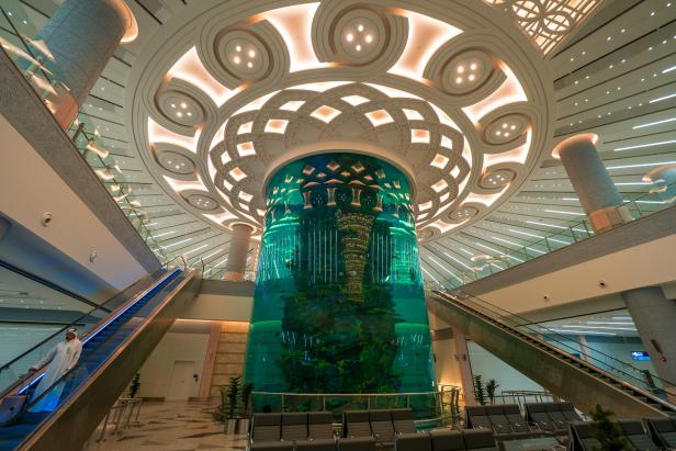 Ein großes Aquarium steht in einem modernen Gebäude mit Rolltreppen.