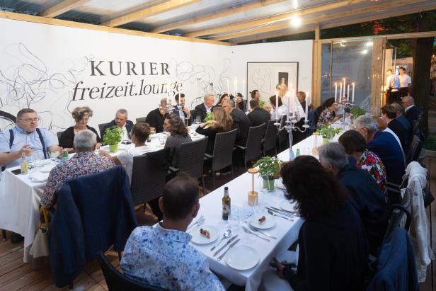 Gäste sitzen an langen Tischen bei einer Veranstaltung des „Kurier freizeit.lounge“.