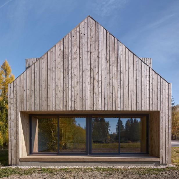 Ein modernes Holzhaus mit großen Fensterfronten unter blauem Himmel.