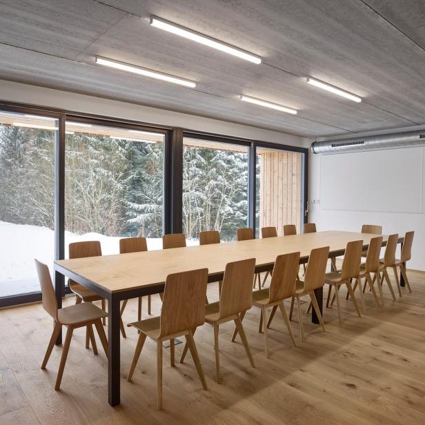 Ein Konferenzraum mit einem langen Holztisch und Blick auf einen verschneiten Wald.