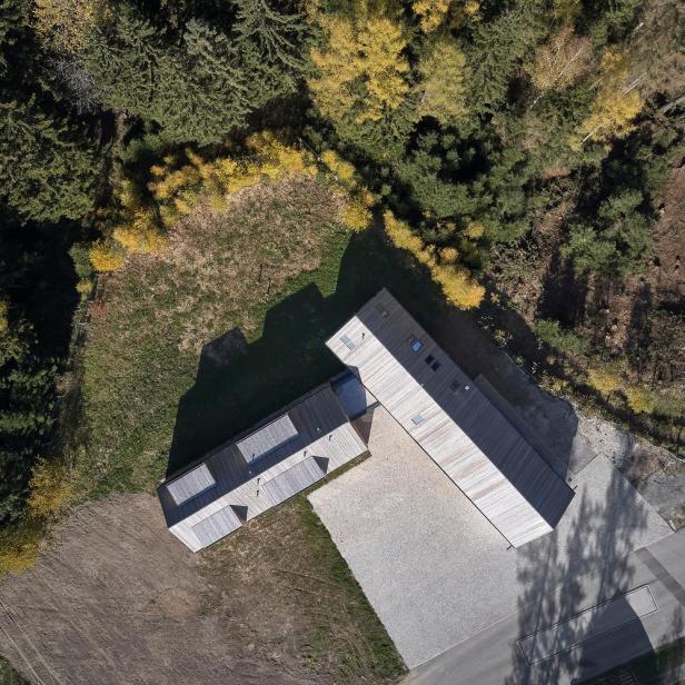 Luftaufnahme von zwei modernen Holzhäusern am Waldrand.
