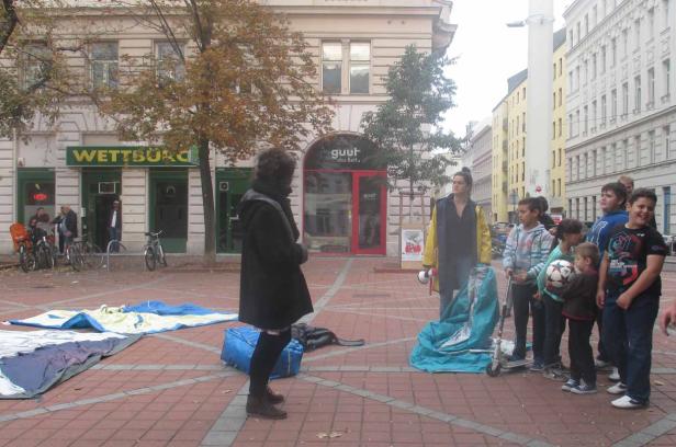 Eine Gruppe von Kindern und zwei Frauen stehen auf einem Platz in der Stadt.
